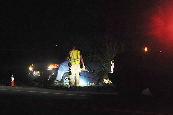 A fireman looks over the scene near mile marker 200 at approximately 10 p.m. Wednesday, Sept. 26, along highway 101 where this vehicle went off the roadway into the ditch. Photo by Lonnie Archibald