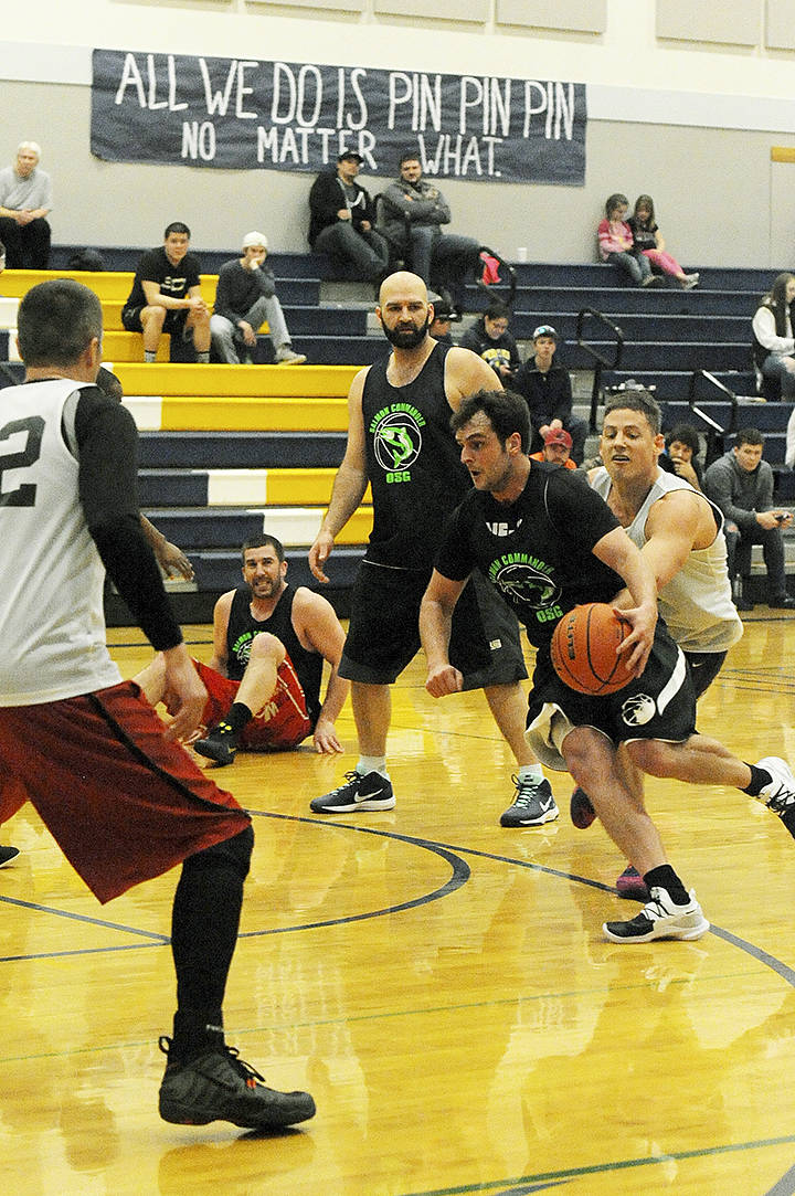 Olympic Sporting Goods’ ex-Spartans Kasey Ulin (left) and DJ Huggins look on while another ex-Spartan Jordan Justus drives the key Sunday during the Nate Crippen Memorial Basketball Tournament in Forks. The Olympic Sporting Goods defeated Black Diamond Electric 69-61 to take the championship. Photo by Lonnie Archibald