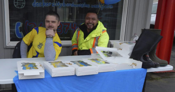 Sergei Holmquist on the left, in the photo, was joined by Juan Almazan for support. Empty boots on the table await donations for Ukraine on Friday afternoon outside Decker City Hardware. Photo Christi Baron