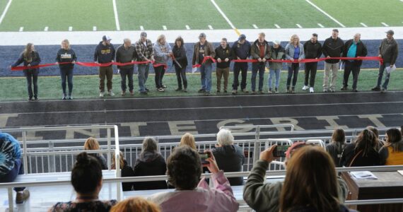 Spectators in the stands photograph the Forks Chamber of Commerce Ribbon Cutting Ceremony with cell phones during the Spartan Stadium dedication held on April 14 at the new Spartan Stadium in Forks. Photo by Lonnie Archibald