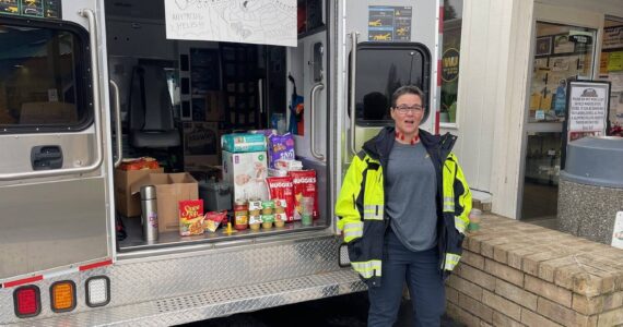 Ambulance crew member Adria Williams was one of several who set up outside Forks Outfitters last week collecting food and cash to benefit the Forks Food Bank. Photo Christi Baron