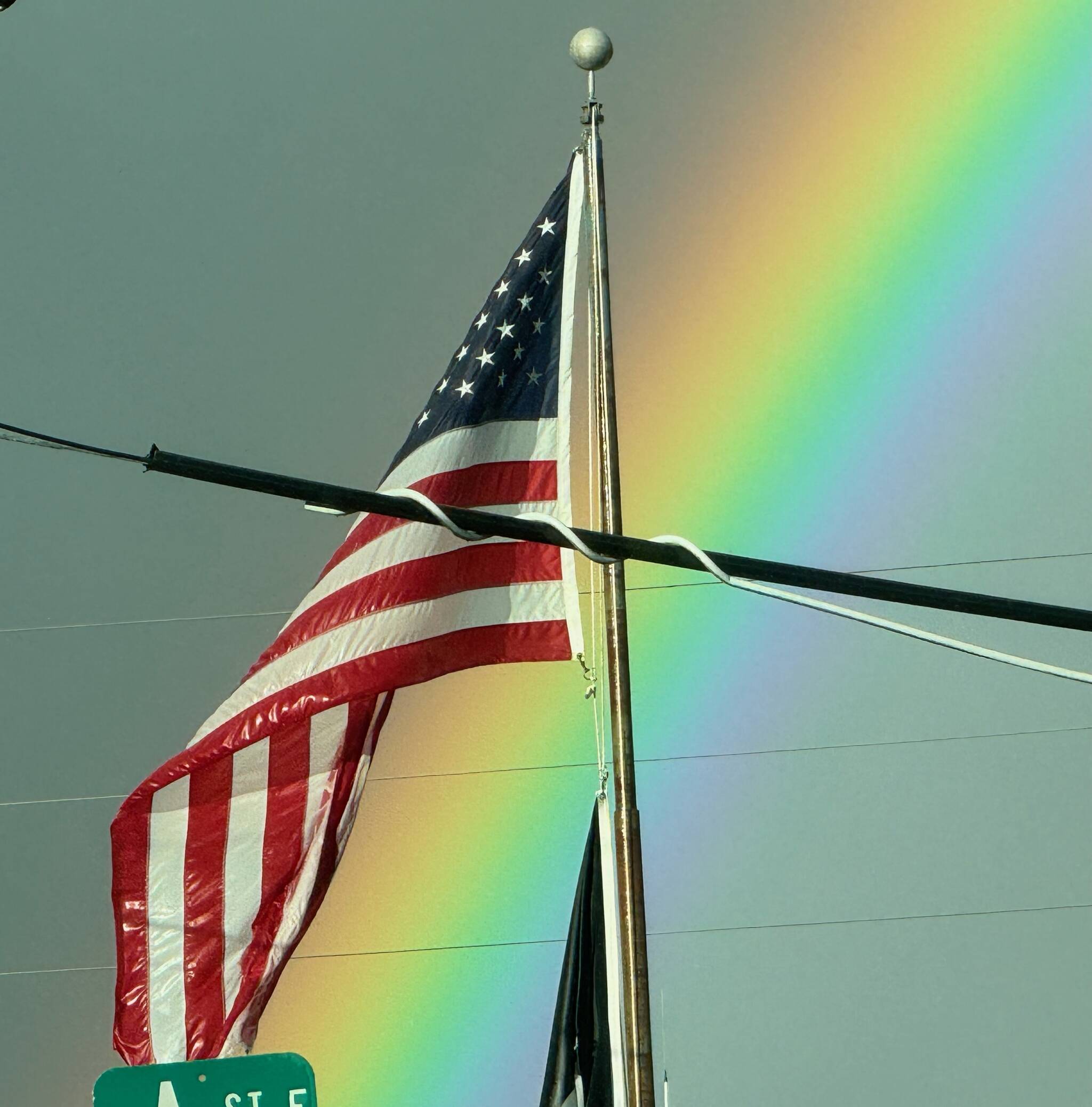 A wet flag flies over the Forks Post Office …with a rainbow backdrop. Photo MJ Ashue