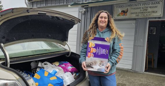 Sena Engeseth, Forks Food Bank, recently accepted donated pet food from Friends of Forks Animals. The pet food was donated by generous community members from the Forks area to Friends of Forks Animals. Submitted photo