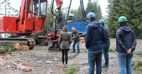 Center of photo Forks Chamber Logging and Mill Tour guide Randy Mesenbrink demonstrates how some of the machinery on the landing works. Tour participants from New York and London look on, last Wednesday on a Dahlgren Logging job on Owl Mountain. Photo Christi Baron