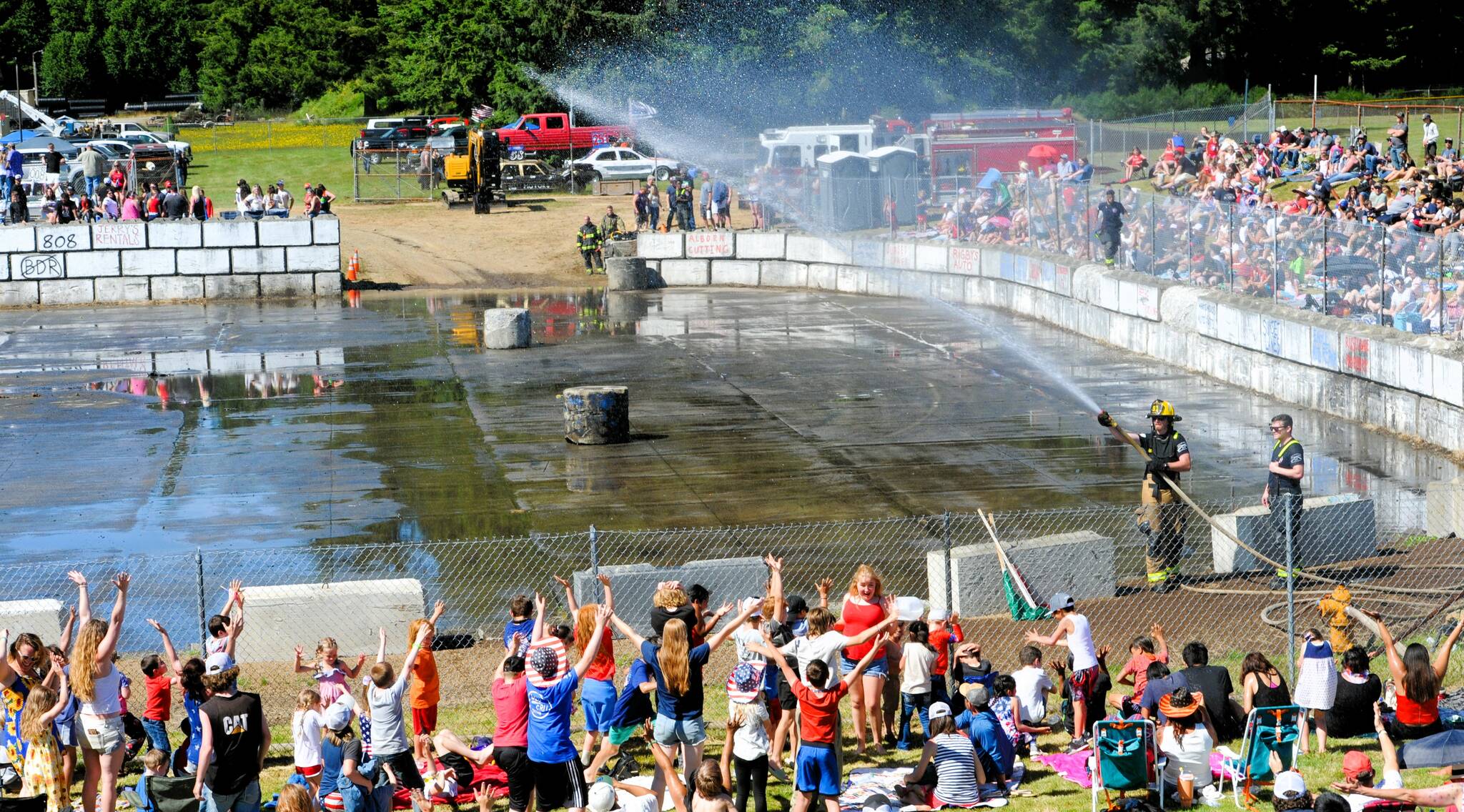 Local firemen helped hot demo derby fans cool off between heats. Photo by Lonnie Archibald