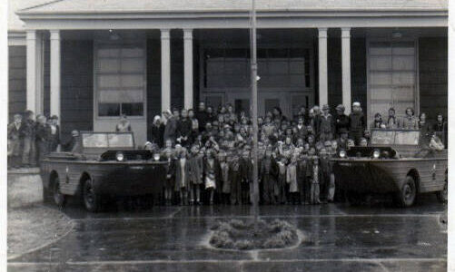 This photo was taken in 1942 outside the School’s Annex building. At the time the building may have served grade school children. The reason for and who is in the photo has been lost to time.
Adria Fuhrman brought the photo into the Forks Forum hoping that someone who was in the photo might remember the occasion or may have heard from someone who was in the photo what was going on here.
May be associated with the Quillayute Naval Air Station or some other branch of the military? Thanks for any information on this photo!