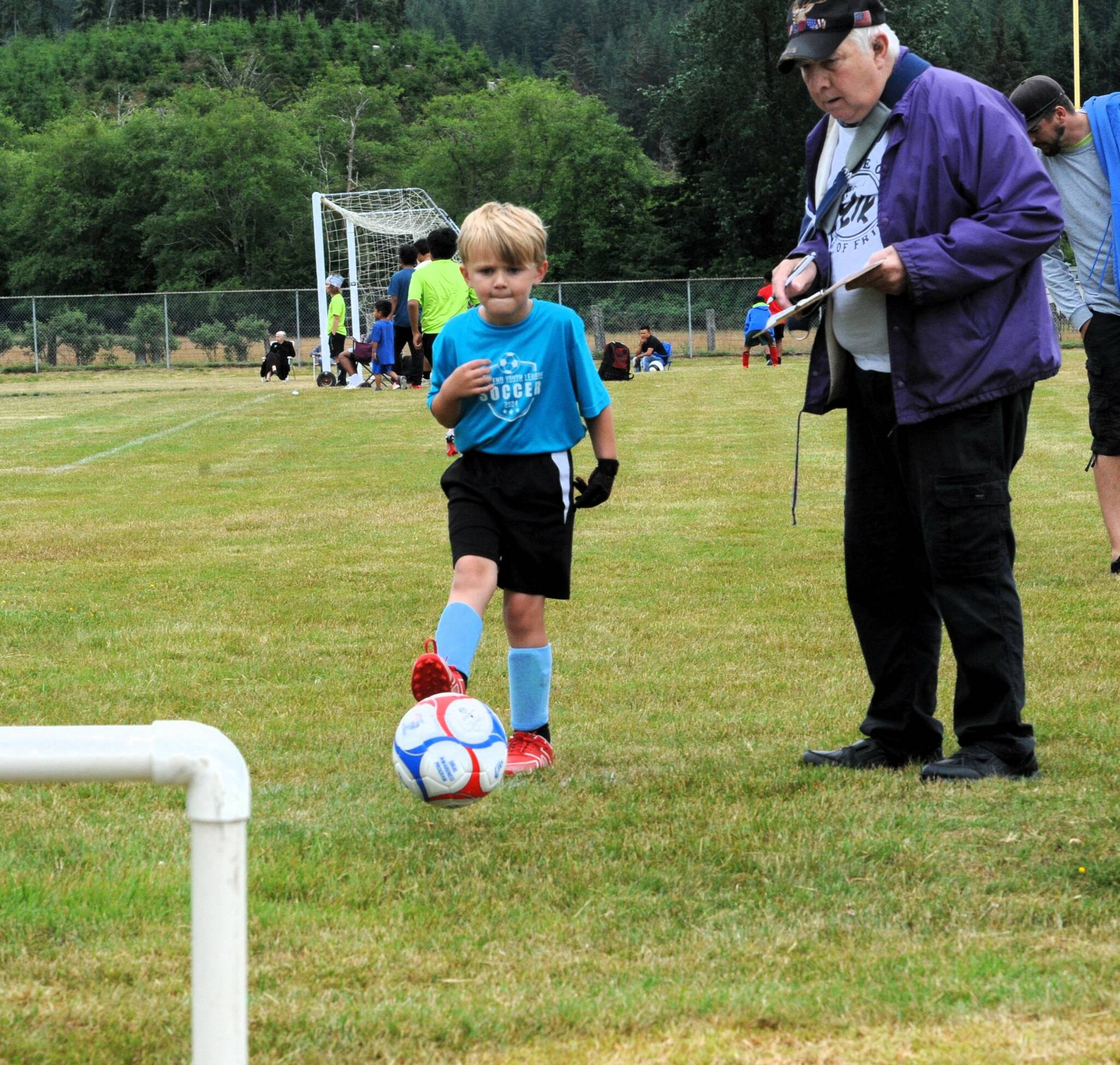 With Elks member Chuck Jennings keeping score, six-year-old Huxley Weekes kicks towards the goal.