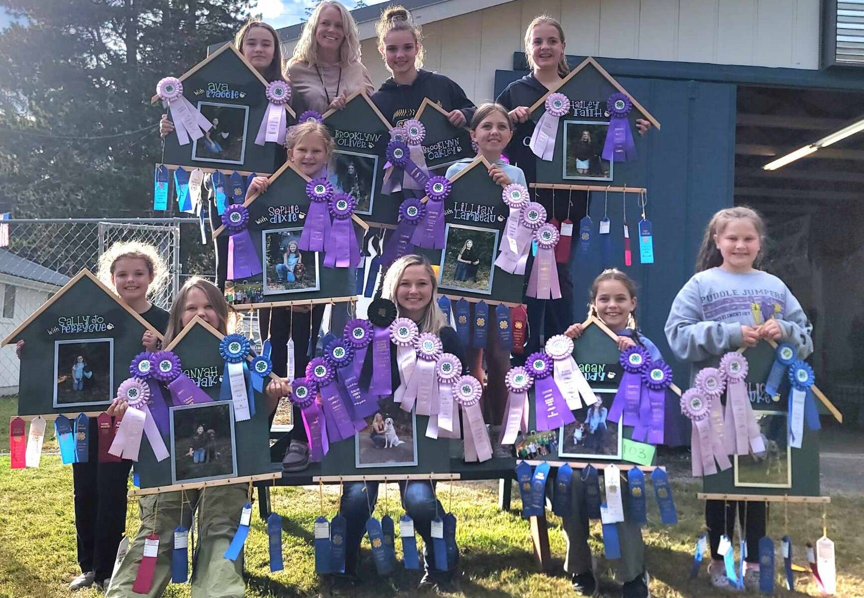 Members of the Forks Happy Tails 4-H group hold photos of their dogs decorated with ribbons won at the Clallam County Fair this past weekend. Top -Ava Baker and Maggie, Leader Carrie Simons, Brooklynn Rondeau with Oliver and Oakley, and Hailey Rondeau with Faith. Middle…Sophie Davis with Dixie, Lillian Crippen with Lambeau. Bottom…Sally Baker with Perry Sue, Hannah Rasmussen with Kodak, Zoie Davis with Belle, Reagan Hull with Trudy, and Alice Rasmussen with Luke. Photo Nerissa Davis