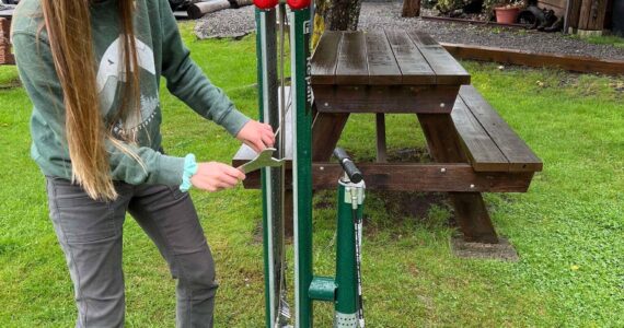 Provided through a grant from the Olympic Peninsula Visitor Bureau, the Forks Chamber purchased a bike rack and repair station for the VIC/Timber Museum grounds. These pieces were added so that bicyclists traveling through could rest and repair their bikes at a safe location. With the help of Olympic Corrections Center Community Crews, they were installed over the last two weeks.
Pictured: Kari Larson, Forks Chamber Director of Customer Service, inspects the new additions! Submitted photo