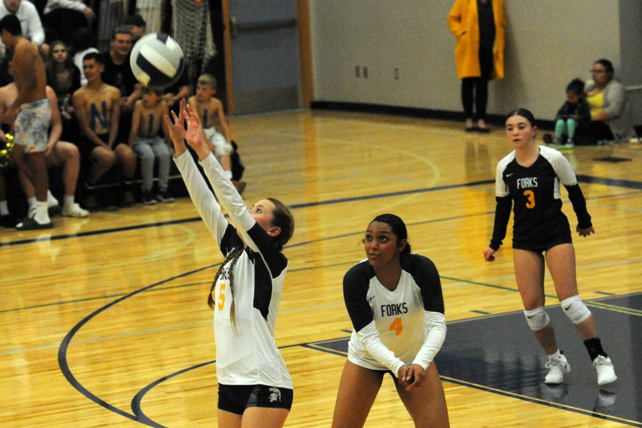 Spartan Reagan Dunn (5) hits while teammates Eladia Hernandez-Stansbury (4) and Kylie Hull look on. Forks defeated Chief Leschi 3 to 0 in the Spartan Gym on Oct. 3. Photo by Lonnie Archibald