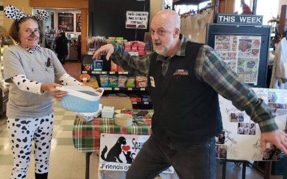 All Darren Sackett, from Forks Outfitters, needed was a drumroll as he struck a dramatic pose as he drew the winning ticket for the Friends of Forks Animals Halloween Basket. Betsy Cadwell, FOFA member, is assisting. The lucky winner was Mary Ulin!
The basket and contents were donated by FOFA members Karen Clark and Deb Pavlich Boaz.
Thanks to everyone who bought tickets!! Submitted photo