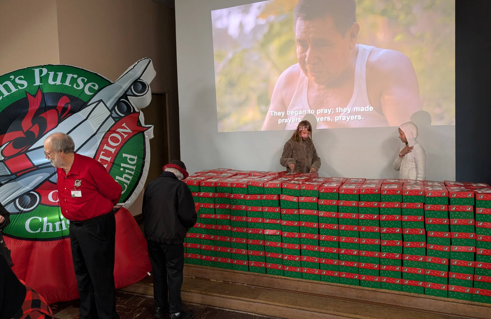 Left, boxes destined for those in need lined the stage area of the Congregational Church fellowship hall last Saturday as a video played sharing the story of Operation Christmas Child. Photo Deborah Dillon