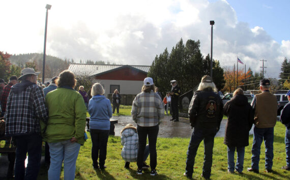 Dave Williams center of the photo offers a Veteran’s Day message to about 50 West End residents who gathered at the Gold Star Families Memorial Monument at the Forks Transit Center on Monday morning. Pastor Bob Schwartz, First Baptist Church, offered prayer, and Megan Rasmussen ended the ceremony with TAPS. It was raining up until 11 a.m. and then blue sky appeared (seen in the corner of the photo)! Williams, who is a weatherman….took credit for the break in the rain. Photo Christi Baron